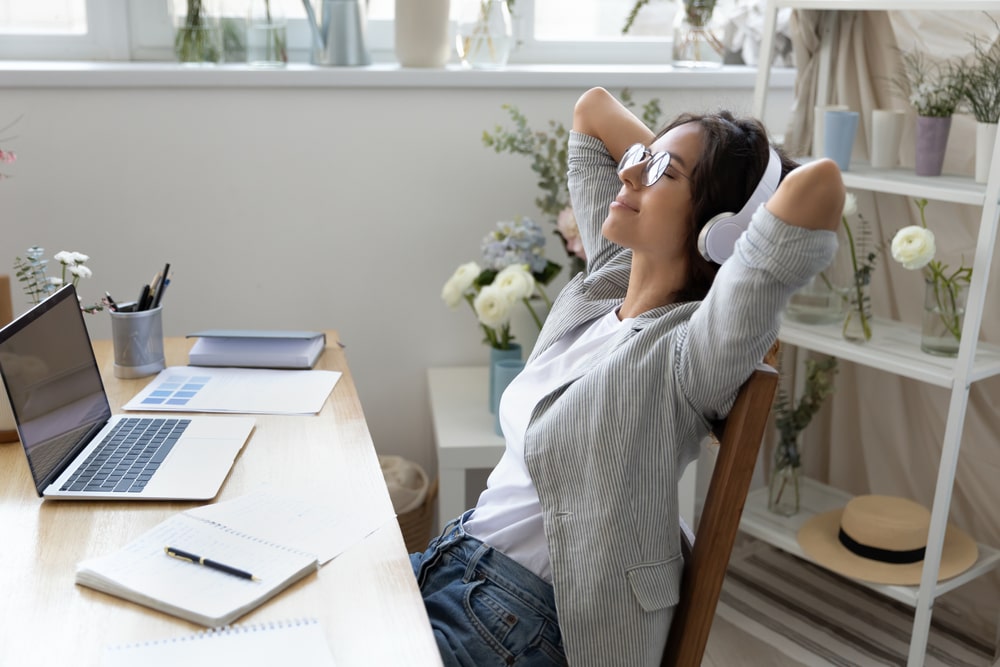 A relaxed woman in headphones enjoying clean, fresh air at her home office, embodying the benefits of good indoor air quality in New Orleans