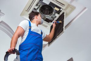 Worker repairing ceiling air conditioning unit - hvac new orleans - authentic air