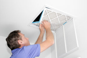 Mature man taking out his hvac grills from a home ceiling air return vent. Hvac New Orleans.